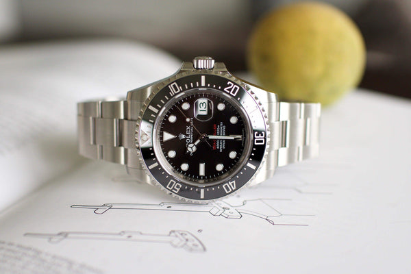 Stainless steel luxury dive watch with black dial and date display on open book background