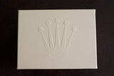 Beige luxury watch box with embossed crown logo on dark background