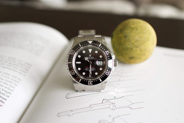 Stainless steel Rolex Sea-Dweller 126600 luxury watch with black dial on open book