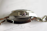 Side close-up of stainless steel luxury watch case and crown with bracelet