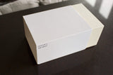 White luxury watch box labeled 'Oyster S SAP 39137' on a dark surface