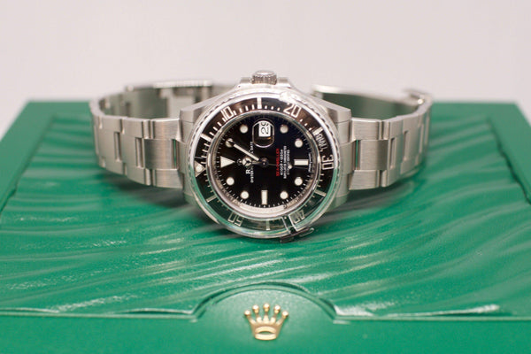 Stainless steel diver watch with black dial and ceramic bezel on green textured box