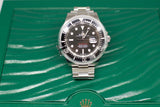 Stainless steel diver watch with black dial and date, displayed on textured green box