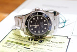Stainless steel luxury dive watch with black dial and bezel, displayed on certification papers