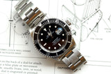 Rolex Submariner luxury dive watch with black dial and steel bracelet on technical blueprints