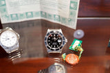 Two luxury Swiss watches and a wax seal on a dark reflective surface.