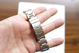 Close-up of a silver luxury watch stainless steel bracelet held in a person's hand