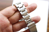Close-up of a stainless steel luxury watch bracelet held in a person's hand.