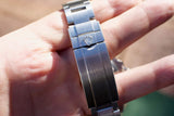 Close-up of a stainless steel Rolex watch bracelet clasp on a person's hand