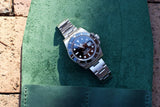 Rolex Submariner luxury dive watch with black dial and silver band on a green leather surface