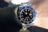 Close-up of a Rolex Submariner luxury watch with a black dial and steel bracelet on a wrist.