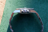 Side view of a luxury silver stainless steel wristwatch on a green textured surface