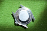 Stainless steel watch case back on a green textured background