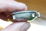 Close-up of a stainless steel luxury watch case side showing the material engraving.