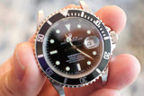 Close-up of a pre-owned Rolex Submariner luxury watch with a black bezel and dial.