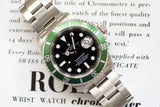 Stainless steel luxury dive watch with green bezel and black dial on printed text background