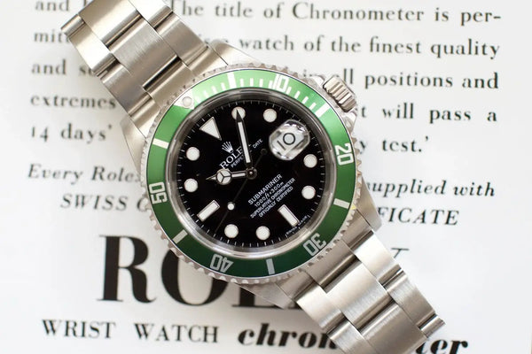 Stainless steel luxury dive watch with green bezel and black dial on printed text background