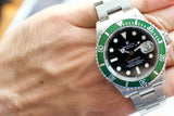 Stainless steel luxury dive watch with green bezel and black dial on wrist