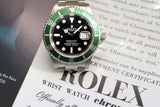 Stainless steel luxury dive watch with green bezel and black dial on official certificate