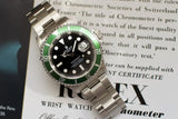 Stainless steel watch with green bezel and black dial on official certificate
