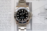Stainless steel luxury dive watch with black bezel and dial, displayed on an open book