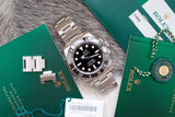 Stainless steel luxury dive watch with black bezel and dial, displayed with green certification cards and tags.