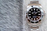 Stainless steel Rolex Submariner No Date luxury watch with black dial and bezel on textured surface