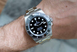 Stainless steel luxury dive watch with black dial and bezel on wrist