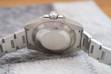 Back view of stainless steel luxury watch case and bracelet on textured surface