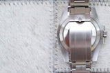 Stainless steel luxury dive watch caseback and bracelet detail on soft fabric