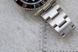 Stainless steel Swiss dive watch bracelet and bezel close-up on light-textured surface