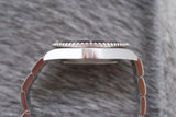Side view of stainless steel luxury watch case and bracelet on textured background