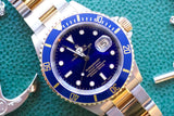 Close-up of a Rolex Submariner luxury watch with a blue dial and two-tone gold and steel band.
