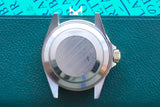 Rear view of a stainless steel luxury watch case on a green textured surface
