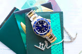 Rolex Submariner luxury watch with blue bezel and two-tone band on a green leather case