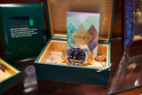 Rolex luxury watch with blue bezel in a green presentation box with documentation