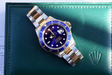 Rolex Submariner luxury watch with blue bezel and two-tone silver and gold band on green box