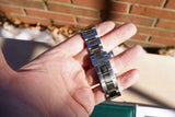 Close-up of a stainless steel Rolex watch bracelet held in a hand