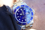 Close-up of a Rolex Submariner luxury watch with a blue bezel and two-tone steel and gold band.