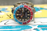 Vintage stainless steel watch with red and blue bezel, black dial, and date display