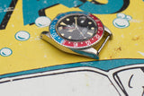 Vintage luxury watch with blue and red bezel and black dial on colorful background