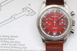 Vintage Sandoz chronograph watch with red dial and brown leather strap on technical manual.