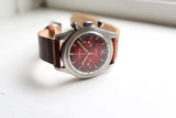 Vintage Sandurz chronograph luxury watch with a brown leather strap on a white surface