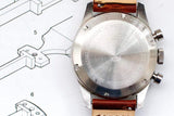 Back view of a stainless steel luxury Swiss watch with a brown leather strap.