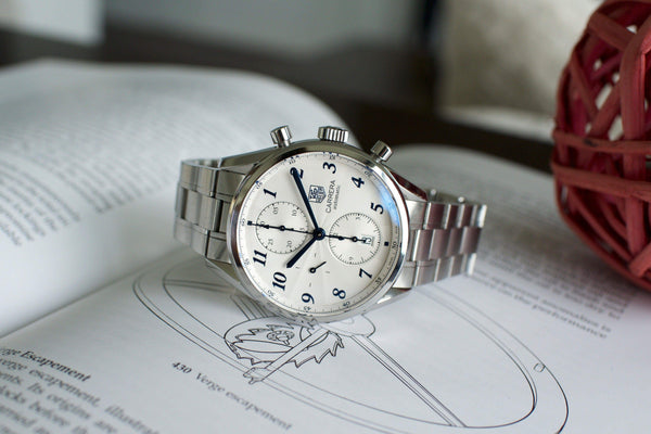 IWC Portugieser Caprera automatic chronograph luxury watch with silver band on a book
