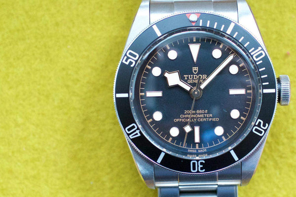 Stainless steel automatic dive watch with black bezel and round hour markers on yellow background