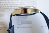 Side view of polished stainless steel luxury watch case with navy blue leather strap