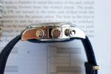 Side view of a luxury chronograph watch with polished steel case and black strap