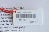 Watch tag with red string, barcode, and Tudor 01 label on text background