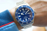 Blue dial titanium diver watch with date on wrist, featuring luminous markers and rotating bezel